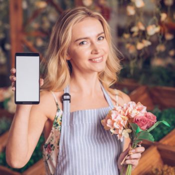 smiling-portrait-blonde-young-woman-holding-bouquet-hand-showing-mobile-phone_23-2148049438-350x350